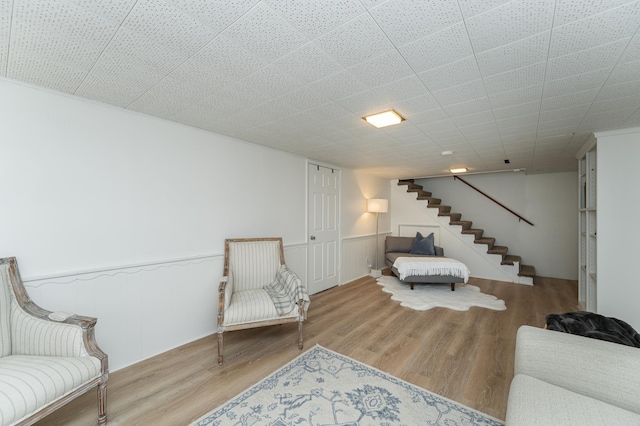 sitting room with wainscoting, stairs, and wood finished floors