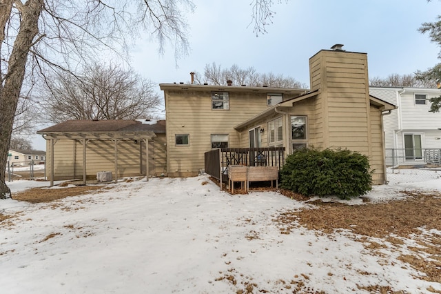 snow covered house with a deck and a chimney