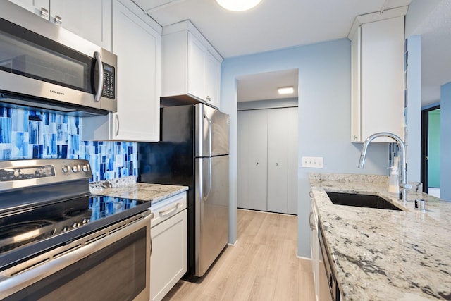 kitchen with appliances with stainless steel finishes, white cabinetry, and a sink