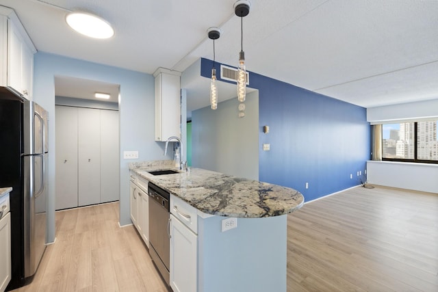 kitchen with a sink, light wood finished floors, appliances with stainless steel finishes, and white cabinetry