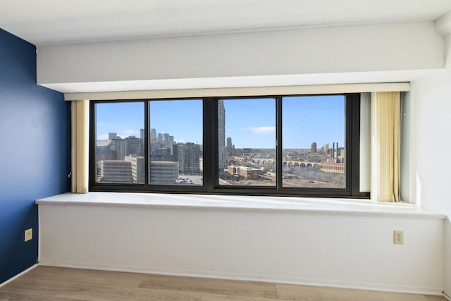 unfurnished room with a view of city, wood finished floors, and baseboards