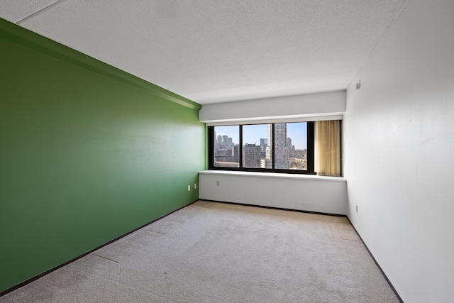 spare room featuring carpet, a city view, and a textured ceiling