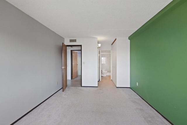 unfurnished room with light carpet, visible vents, and baseboards