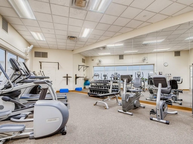 exercise room with baseboards, visible vents, and a drop ceiling