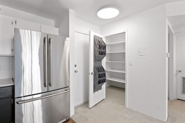 kitchen with light countertops, freestanding refrigerator, and light colored carpet