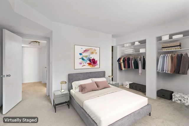 bedroom with light carpet and two closets