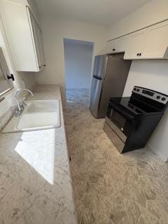 kitchen with light countertops, white cabinets, appliances with stainless steel finishes, and a sink