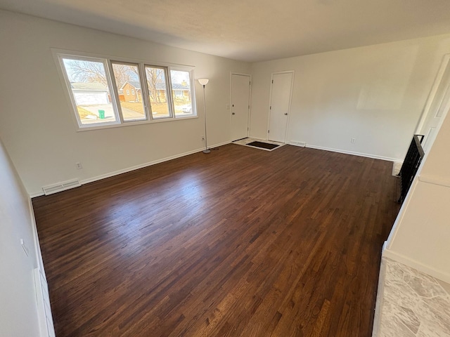 empty room with visible vents, baseboards, and dark wood finished floors