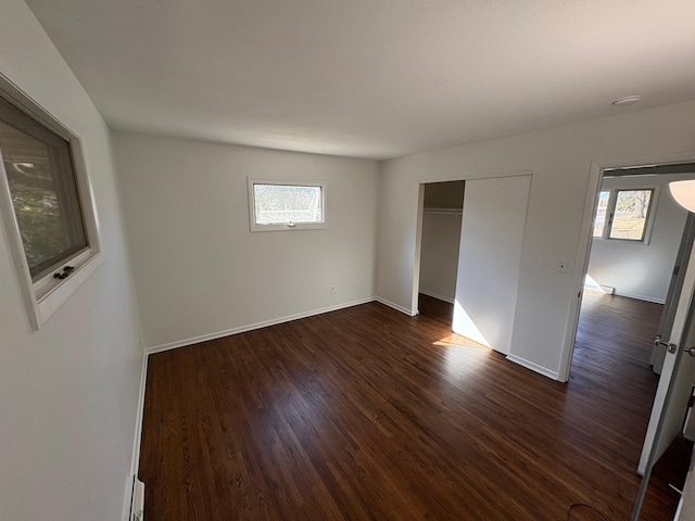 unfurnished bedroom with a closet, baseboards, and dark wood finished floors