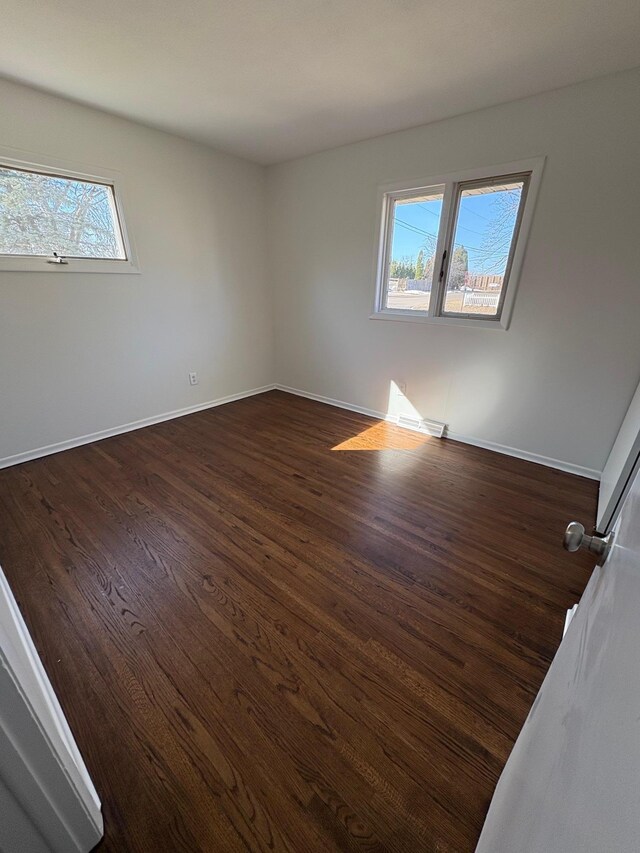 unfurnished room with dark wood finished floors and baseboards