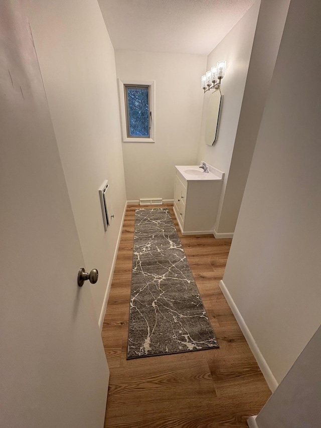 bathroom featuring vanity, visible vents, wood finished floors, and baseboards