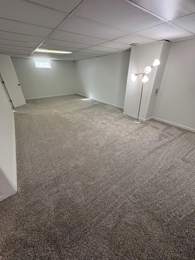 below grade area featuring a paneled ceiling, carpet floors, and baseboards