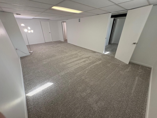 finished basement with baseboards, a paneled ceiling, and carpet