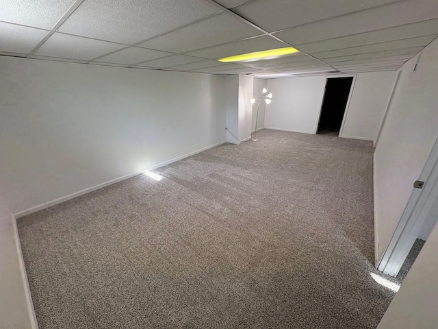 spare room with light carpet, a drop ceiling, and baseboards