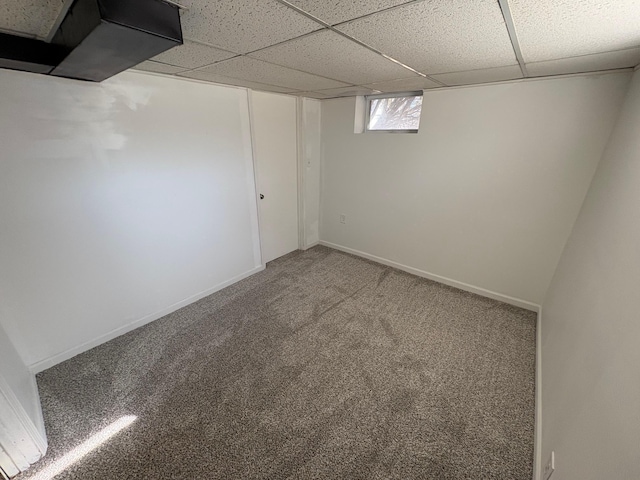 basement with baseboards, a paneled ceiling, and carpet