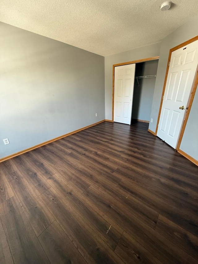 unfurnished bedroom with a closet, baseboards, dark wood-type flooring, and a textured ceiling