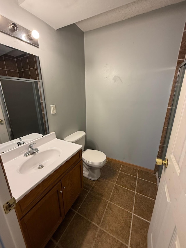 full bathroom featuring vanity, baseboards, tiled shower, tile patterned flooring, and toilet