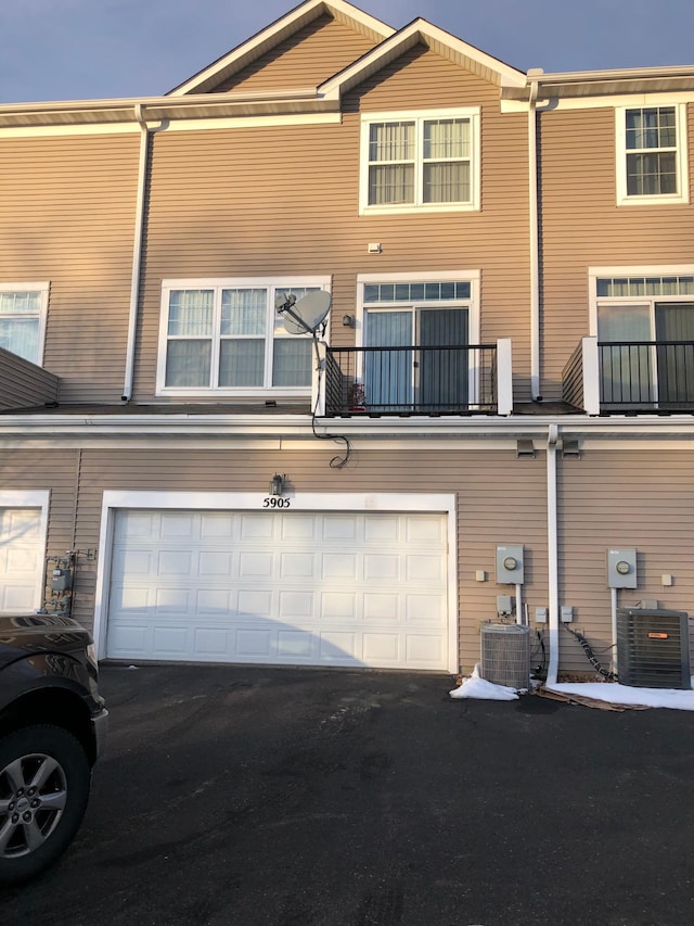 rear view of house with cooling unit, driveway, and a garage