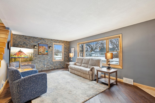 living area with hardwood / wood-style flooring, baseboards, visible vents, and a textured ceiling