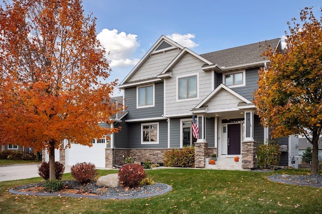 craftsman house with a garage, concrete driveway, stone siding, roof with shingles, and a front yard