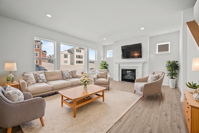 living room with baseboards, recessed lighting, a glass covered fireplace, and light wood-style floors