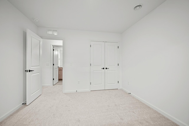 unfurnished bedroom featuring baseboards, visible vents, a closet, and light colored carpet