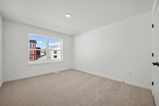 carpeted empty room with visible vents, baseboards, and a textured ceiling