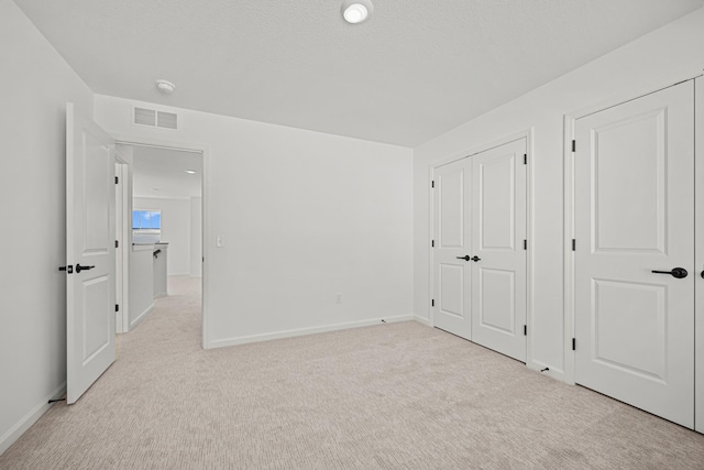 unfurnished bedroom with light carpet, baseboards, visible vents, and a closet