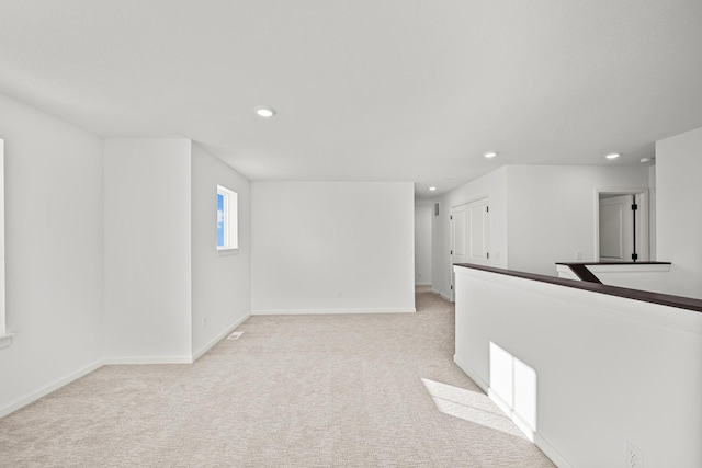 empty room featuring recessed lighting, light carpet, and baseboards