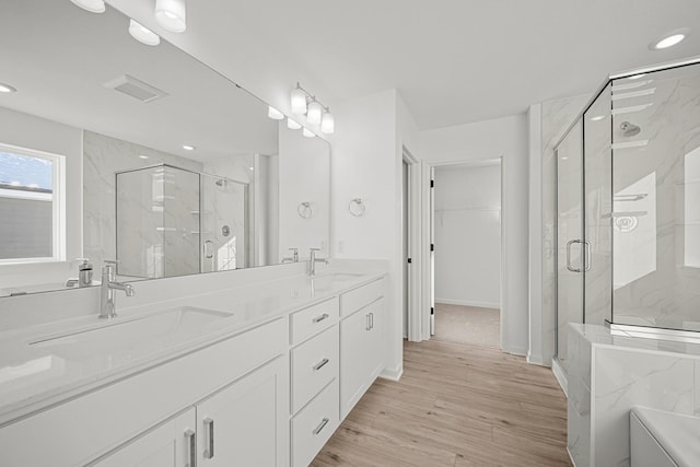 full bathroom with visible vents, wood finished floors, a sink, and a marble finish shower