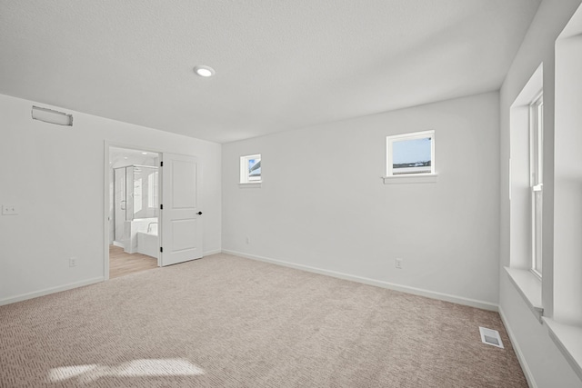 unfurnished bedroom featuring light carpet, visible vents, baseboards, and connected bathroom