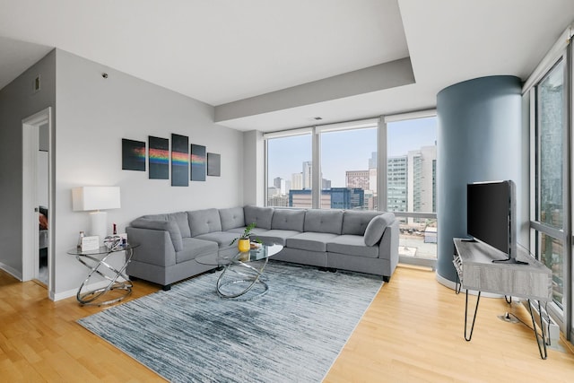 living room featuring floor to ceiling windows, baseboards, and wood finished floors