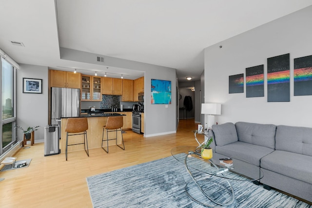 living area featuring visible vents, light wood-style flooring, and baseboards