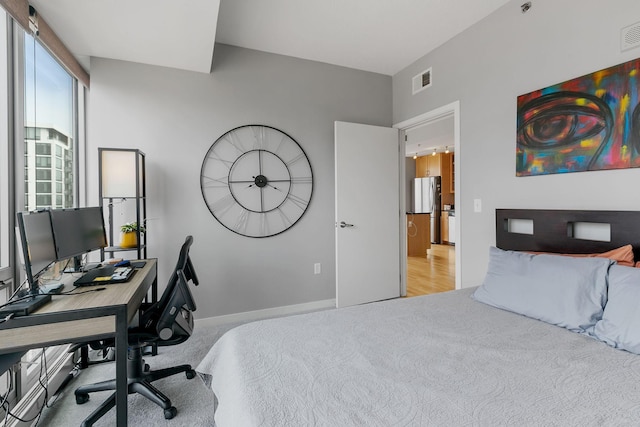 bedroom with baseboards, visible vents, light colored carpet, and freestanding refrigerator