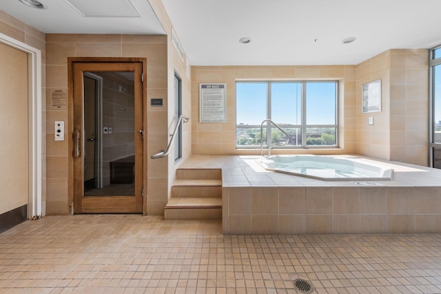 bathroom featuring tile patterned floors, tile walls, recessed lighting, and a bath