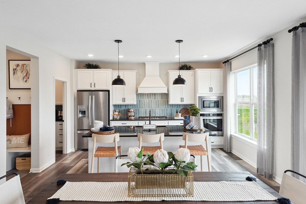 kitchen featuring premium range hood, white cabinetry, appliances with stainless steel finishes, decorative backsplash, and dark countertops