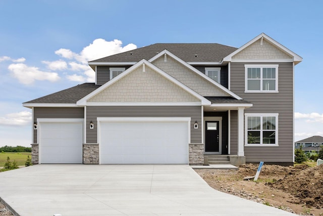 craftsman-style house with an attached garage, stone siding, concrete driveway, and roof with shingles