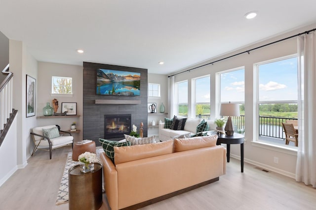 living area with a wealth of natural light, visible vents, light wood finished floors, and a large fireplace