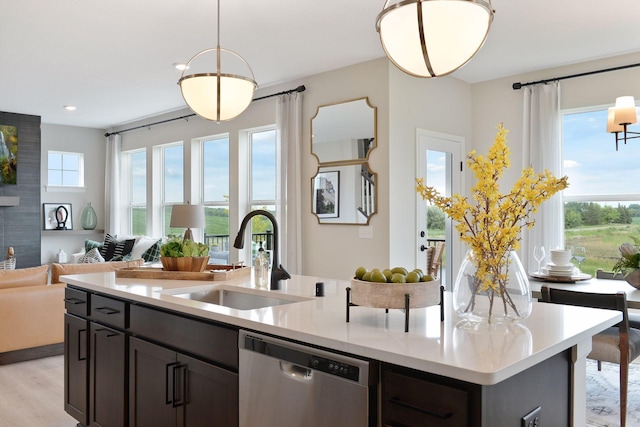 kitchen with pendant lighting, a sink, stainless steel dishwasher, open floor plan, and light countertops