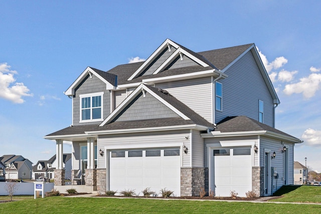 craftsman-style home featuring stone siding, a garage, a shingled roof, and a front lawn