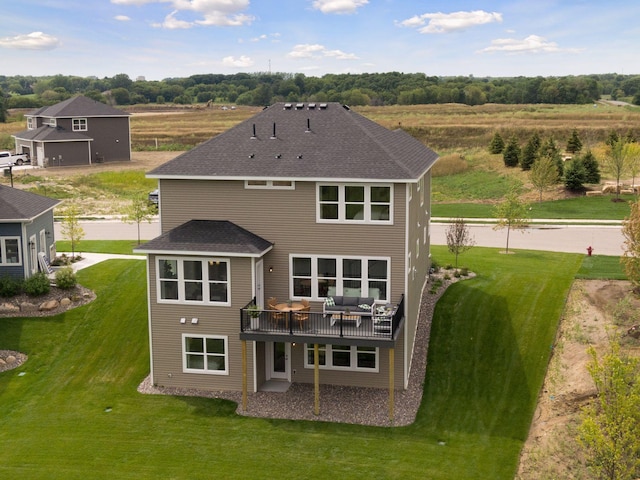 rear view of property with a wooden deck, a lawn, and roof with shingles