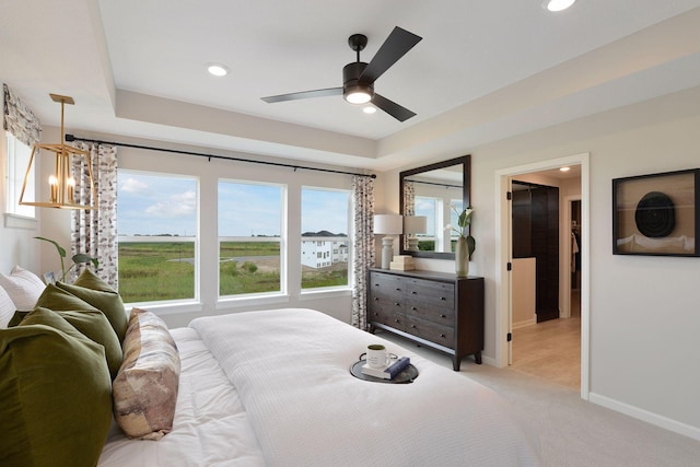 bedroom with baseboards, recessed lighting, a spacious closet, a raised ceiling, and light colored carpet