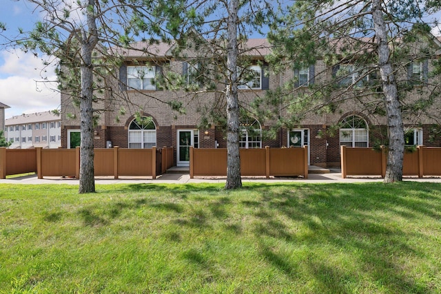 back of house featuring a yard, fence, and brick siding