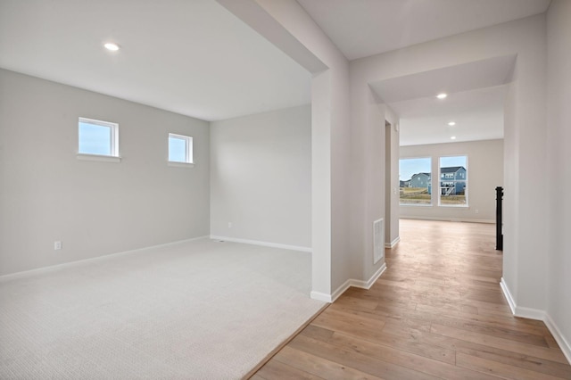 corridor featuring light wood-style floors, plenty of natural light, recessed lighting, and baseboards