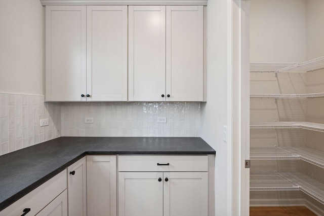 kitchen with dark countertops, white cabinets, and decorative backsplash