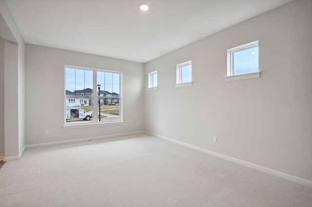 spare room featuring recessed lighting, light colored carpet, and baseboards