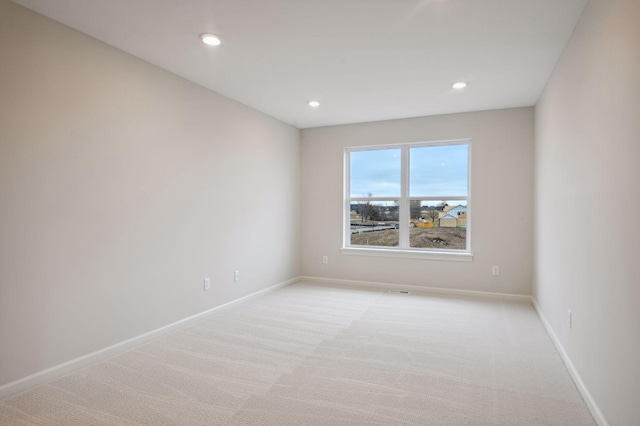 spare room featuring recessed lighting, light carpet, and baseboards