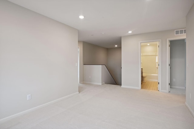 spare room with light carpet, recessed lighting, visible vents, and baseboards