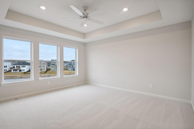 unfurnished room featuring a raised ceiling, visible vents, light carpet, and baseboards