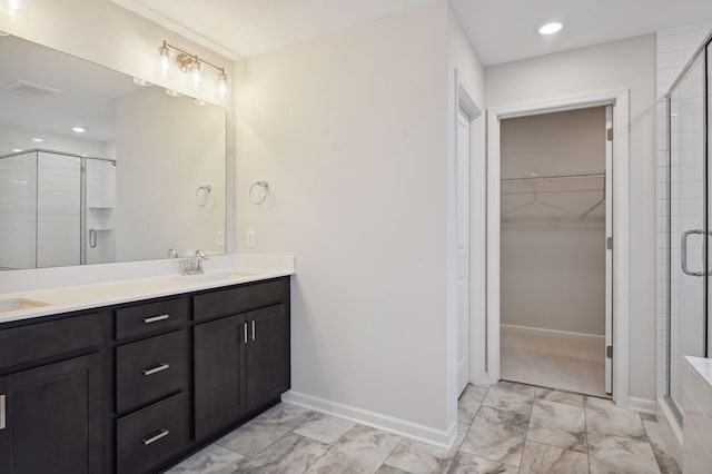 full bathroom with a stall shower, marble finish floor, a sink, and a spacious closet